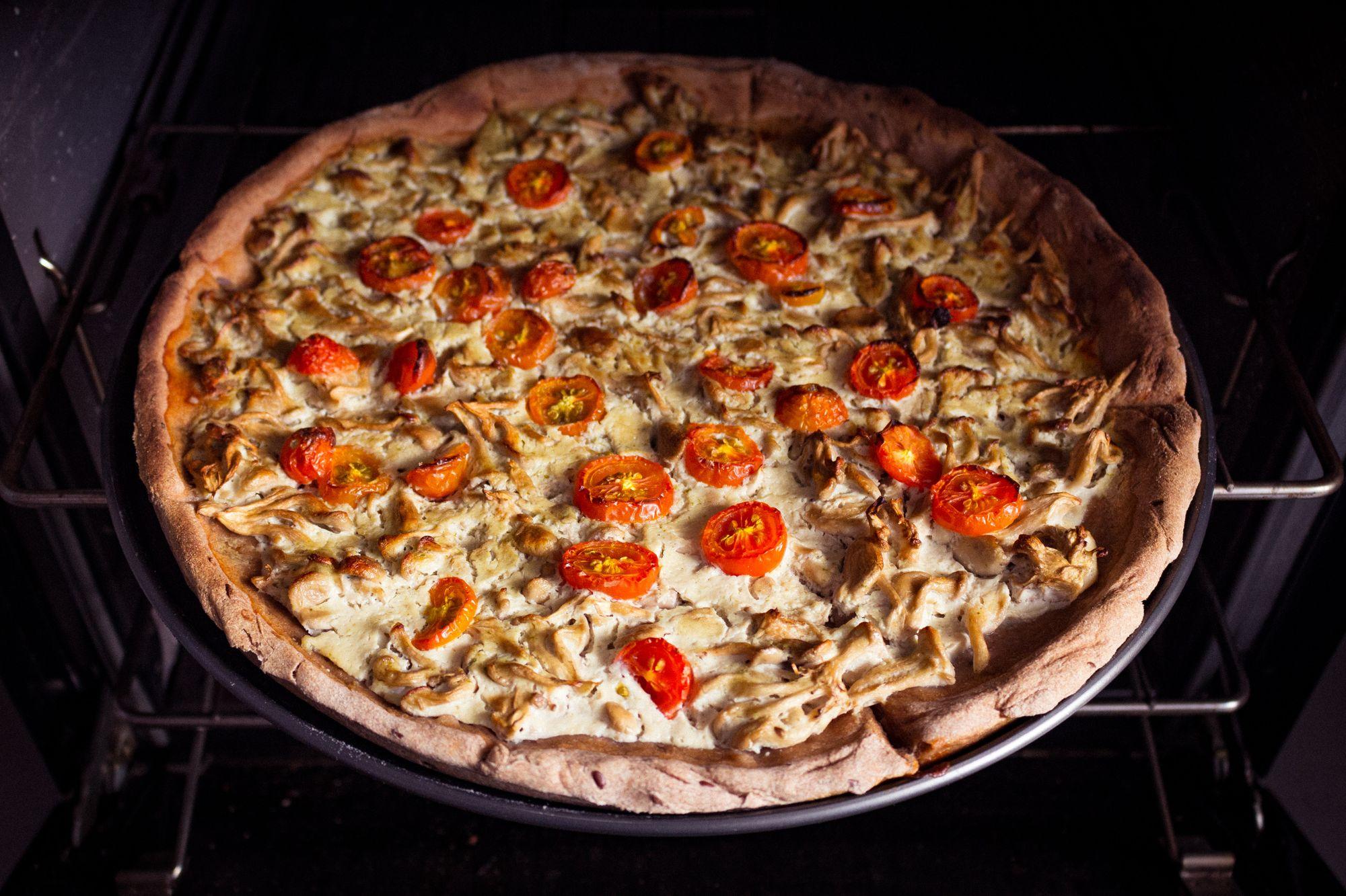 Close-up of a homemade chicken and tomato pizza baking in an oven.